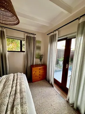 a bedroom with a bed and a sliding glass door at Die Klein Huis in Cape Town