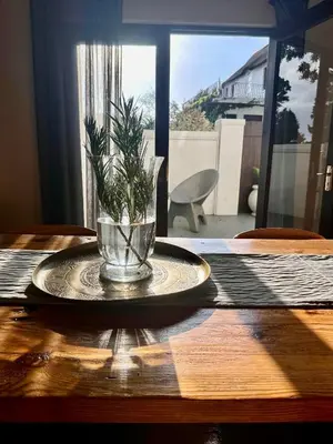 a table with a plate with a plant in a vase at Die Klein Huis in Cape Town