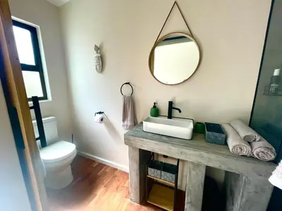a bathroom with a sink and a mirror on the wall at Die Klein Huis in Cape Town