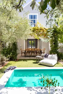 a backyard with a swimming pool and a table at Lush garden 3 bedroom house in Franschhoek