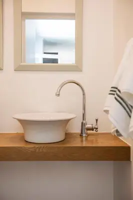 a white sink on a wooden shelf in a bathroom at Lush garden 3 bedroom house in Franschhoek