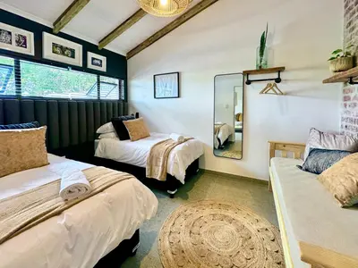 a bedroom with two beds and a mirror at Amsterdam Suite in Cape Town