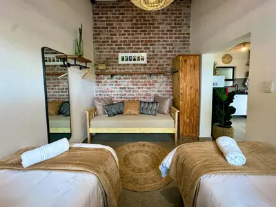 a room with two beds and a couch in it at Amsterdam Suite in Cape Town