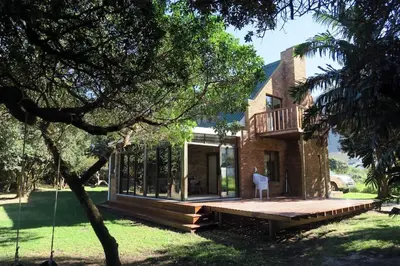 a house with a large deck in front of it at Hidden gem in bush 350m from main beach in Bettyʼs Bay