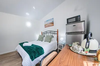a small bedroom with a bed and a refrigerator at Modern & Central 1 BR Apt Close To Major Attractions in Cape Town