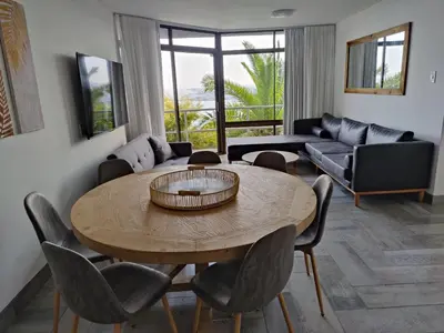 a living room with a table and chairs at Gordon's Bay Sunset View in Cape Town