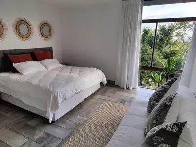 a bedroom with a bed and a large window at Gordon's Bay Sunset View in Cape Town