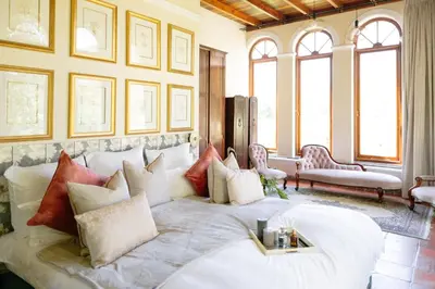 a bedroom with a large white bed with pillows at Manor House at La Roche Estate - Franschhoek in Franschhoek