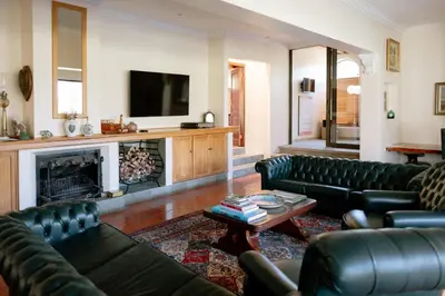 a living room with black leather couches and a fireplace at Manor House at La Roche Estate - Franschhoek in Franschhoek