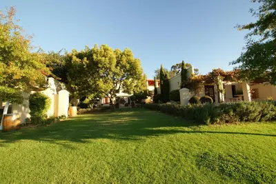 a yard with a green lawn with trees and houses at Cultivar Boutique Hotel in Stellenbosch