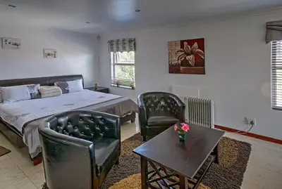 a bedroom with a bed and chairs and a table at TUSCAN VILLA FELICE near West Coast in Cape Town