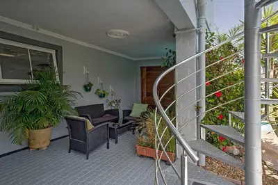 a porch with chairs and plants and a staircase at TUSCAN VILLA FELICE near West Coast in Cape Town