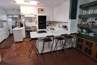 a kitchen with white cabinets and bar stools at Somerset West Family home holiday rental in Cape Town
