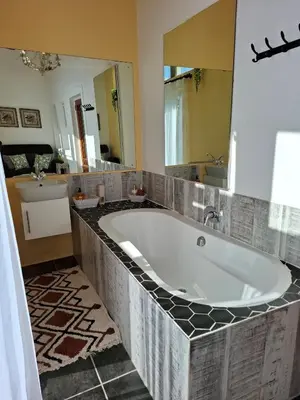 a bath tub in a bathroom with a large mirror at Franschhoek Wine Tram Apartment in Franschhoek