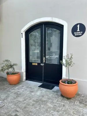 a black door of a building with two potted plants at Franschhoek Wine Tram Apartment in Franschhoek
