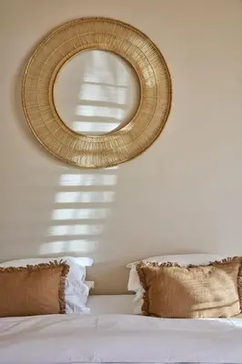 a bedroom with a bed with a rattan mirror on the wall at Kokon Boutique Guesthouse in Somerset West
