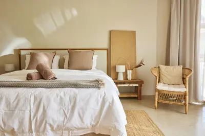 a bedroom with a large bed and a chair at Kokon Boutique Guesthouse in Somerset West