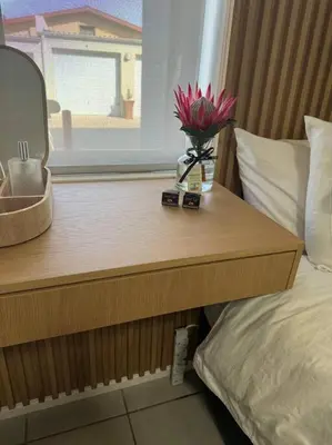 a table with a vase of flowers on top of a bed at Slaap Self Catering in Paarl