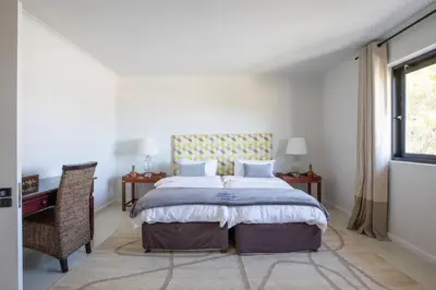 a bedroom with a bed and a desk and a window at Les Baleines Hermanus Villa in Hermanus