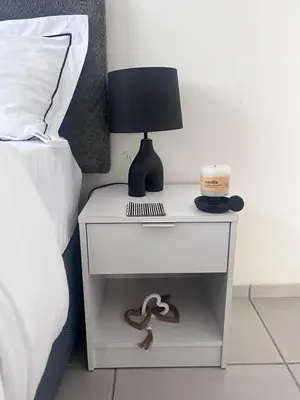 a bedside table with a lamp on it next to a bed at Relaxa Sleep & Go - Self Catering Accommodation in Cape Town