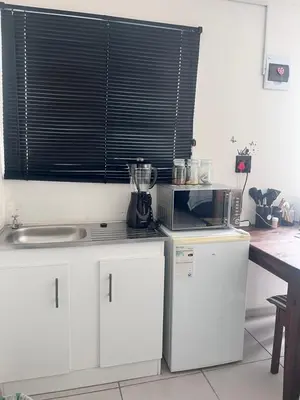 a kitchen with white cabinets and a window at Relaxa Sleep & Go - Self Catering Accommodation in Cape Town