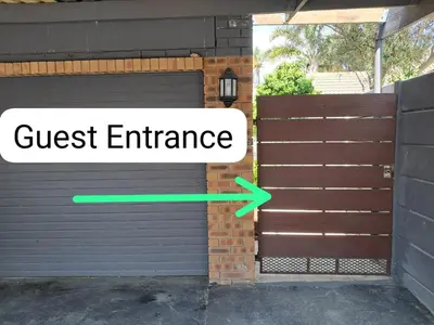 a black garage door with a green arrow pointing to the guest entrance at Ina se Huisie in Blouberg self Catering Apartment in Cape Town