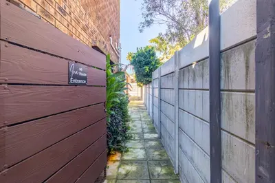 a wooden fence next to a brick wall at Ina se Huisie in Blouberg self Catering Apartment in Cape Town