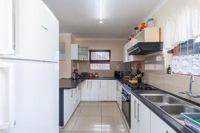 a kitchen with white cabinets and a white refrigerator at Ina se Huisie in Blouberg self Catering Apartment in Cape Town