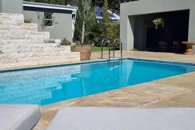 a swimming pool with blue water in front of a house at C'est la Vie 4 in Franschhoek