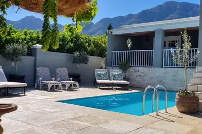 a patio with a pool and chairs and a house at C'est la Vie 4 in Franschhoek