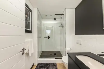 a bathroom with a glass shower and a sink at The Archetype - Nine Palms Luxury Apartments in Cape Town