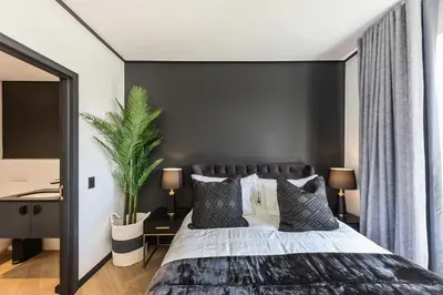a bedroom with a large bed with a black wall at The Archetype - Nine Palms Luxury Apartments in Cape Town