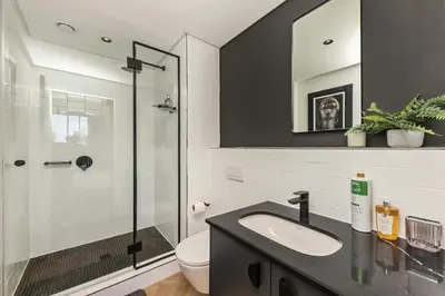 a bathroom with a sink and a glass shower at The Archetype - Nine Palms Luxury Apartments in Cape Town