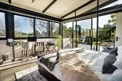 a bedroom with a bed in a room with windows at In-a-Tree in Paarl