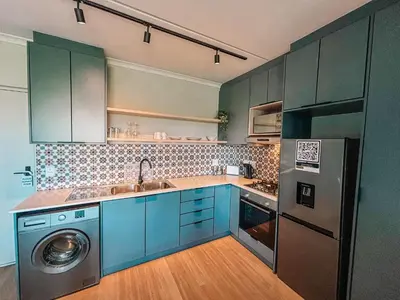 a kitchen with blue cabinets and a washing machine at Cape Mae Apartment Hotel in Cape Town