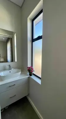 a white bathroom with a sink and a window at The View in Cape Town