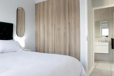 a bedroom with a white bed and a wooden cabinet at The Jade Escape in Cape Town