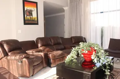 a living room with a brown leather couch and a table at Trinity in Cape Town