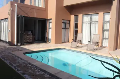 a swimming pool in front of a house at Trinity in Cape Town