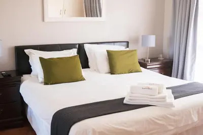 a bedroom with a large white bed with green pillows at Ilanga Du Cap Hotel in Cape Town