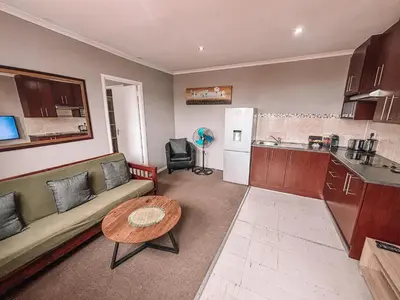 a living room with a couch and a table and a kitchen at Ilanga Du Cap Hotel in Cape Town