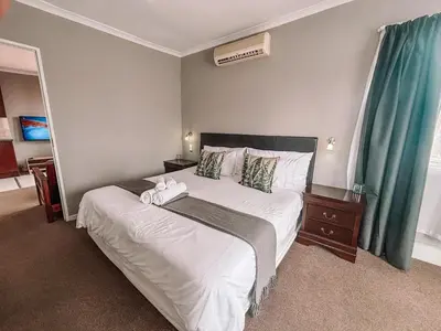 a bedroom with a large white bed with green curtains at Ilanga Du Cap Hotel in Cape Town