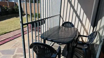 a black table and chairs next to a fence at Leisure Lodges Family Room Parow in Cape Town