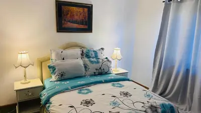 a bedroom with a bed and two lamps and a window at Leisure Lodges Middle Room in Cape Town