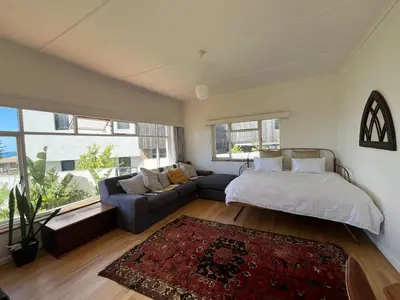 a bedroom with a bed and a couch at Lala Panzi House - Grotto Beach, Voëlklip in Hermanus