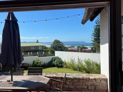 a patio with an umbrella and a table and chairs at Lala Panzi House - Grotto Beach, Voëlklip in Hermanus