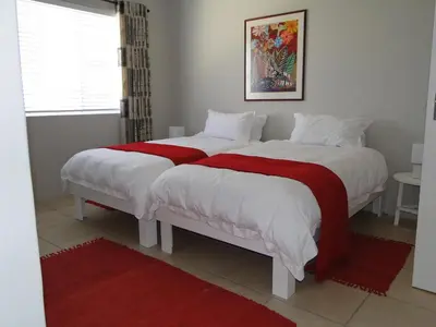 a bedroom with two beds with red and white blankets at Our Nest Guest House in Kleinmond