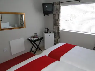 a bedroom with a red and white bed and a television at Our Nest Guest House in Kleinmond