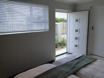 a bedroom with a bed and a large window at Our Nest Guest House in Kleinmond