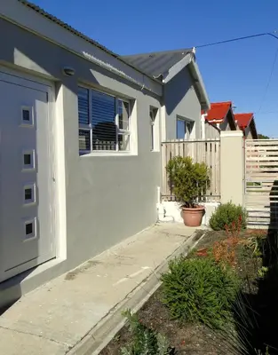 a white house with a door and a fence at Our Nest Guest House in Kleinmond